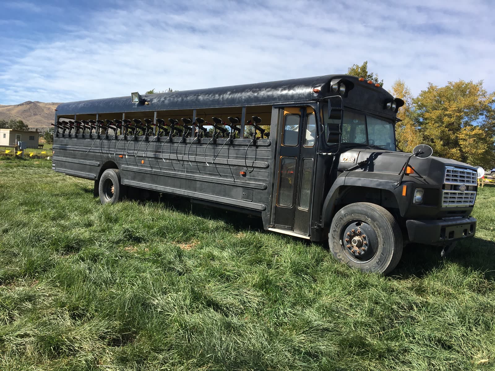 A black armored school bus with open windows parked on the grass at Andelin Family Farm