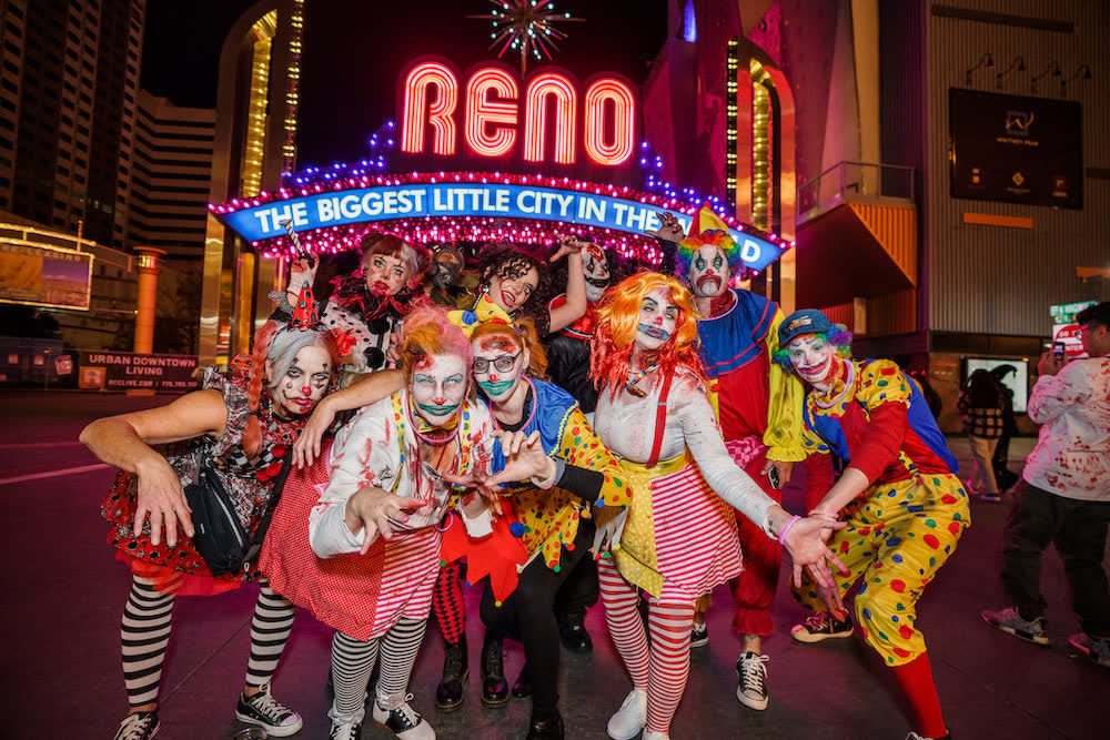 A group in zombie clown costumes poses under the lit Reno Arch during the 2022 Reno Zombie Crawl