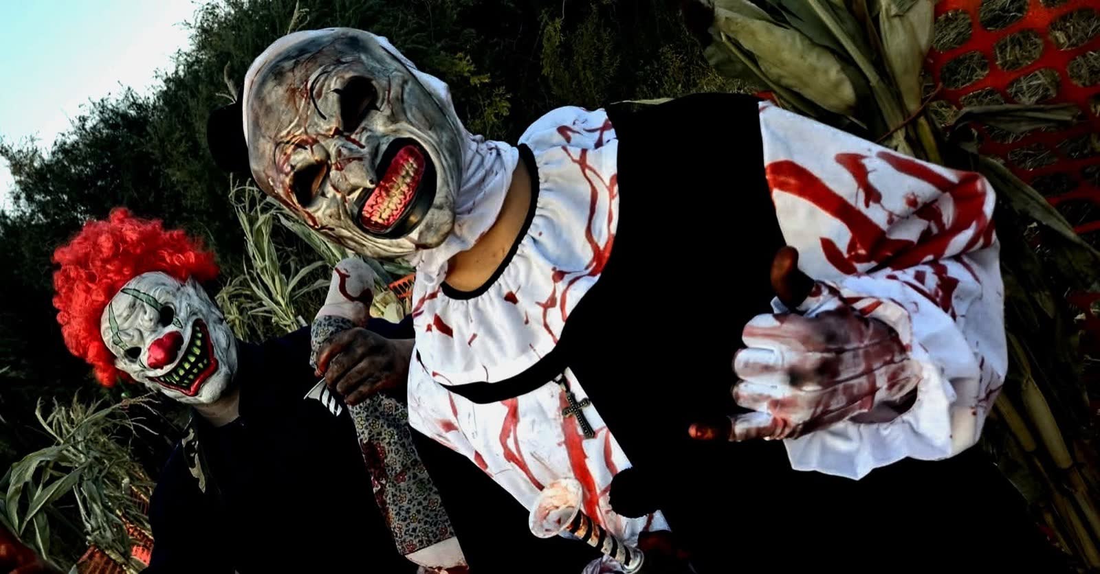 Promotional art for Ferrari Farms' Killer Clown Corn Maze: a masked clown in a blood-spattered costume leaning out of the corn